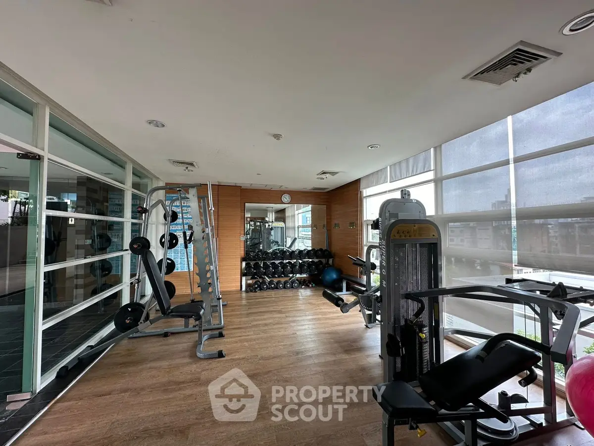 Modern gym with state-of-the-art equipment and wooden flooring in a residential building.