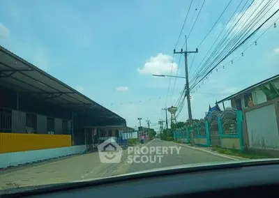 Street view with industrial buildings and clear sky, potential real estate development area.