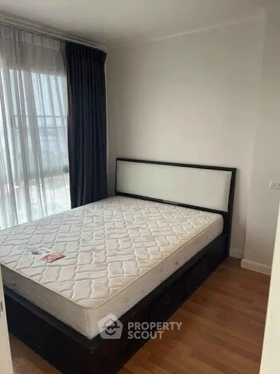 Cozy bedroom with natural light and wooden flooring, featuring a comfortable bed and modern design.