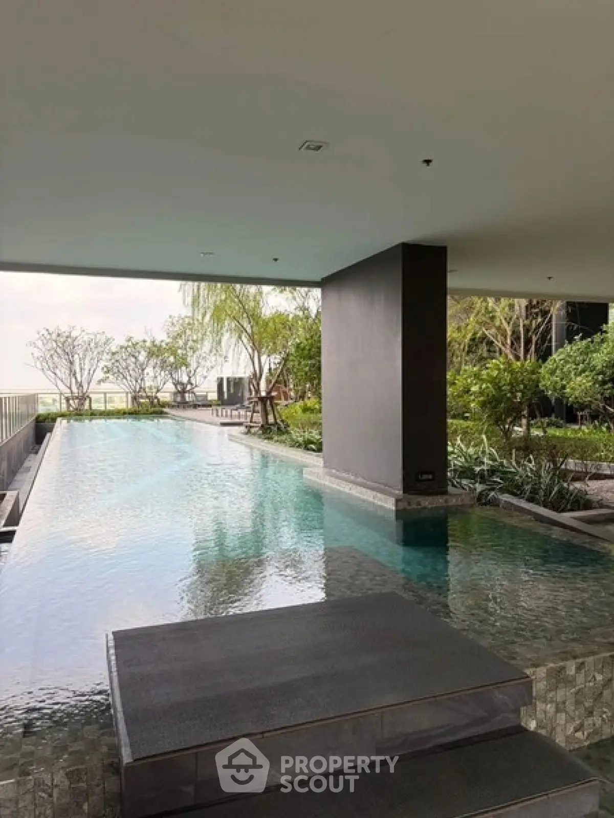 Luxurious modern pool area with lush greenery and serene ambiance in upscale residential complex.