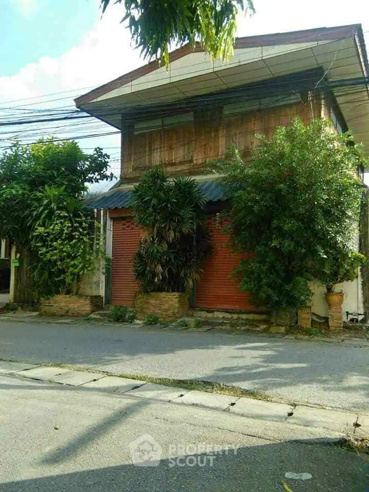 Charming two-story house with lush greenery and rustic wooden facade