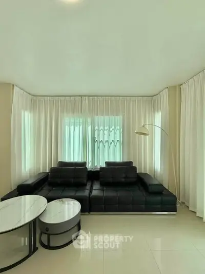 Spacious living room with modern black leather sofa and elegant floor lamp.