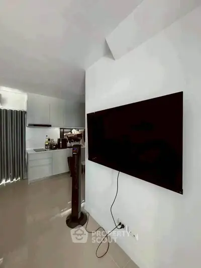 Modern living room with wall-mounted TV and sleek kitchen design