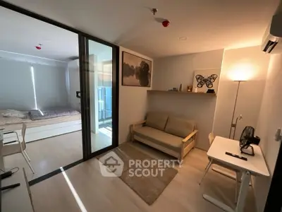 Modern studio apartment with cozy living area and bedroom, featuring sleek furniture and natural light.