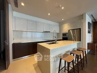 Modern kitchen with sleek island and bar stools, featuring stainless steel appliances and ample cabinetry.