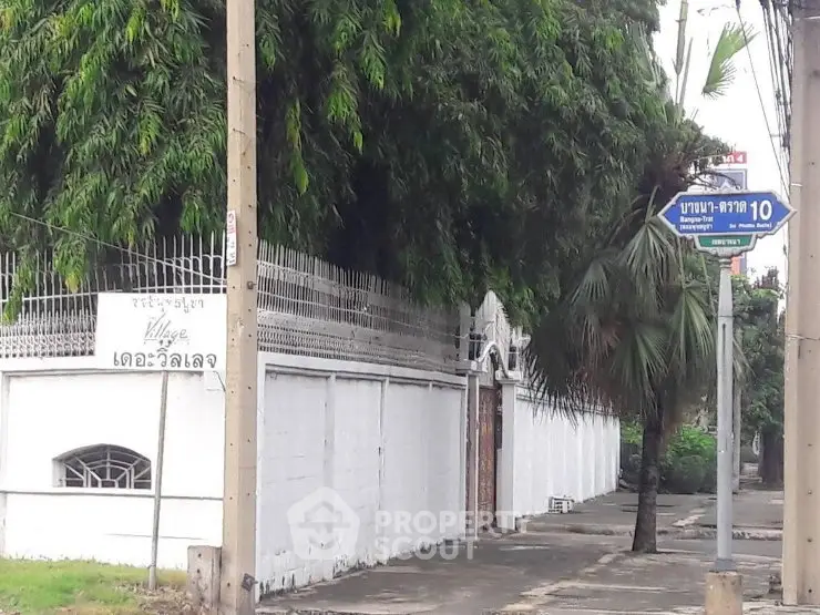 Charming street view of a residential area with lush greenery and a white fence.