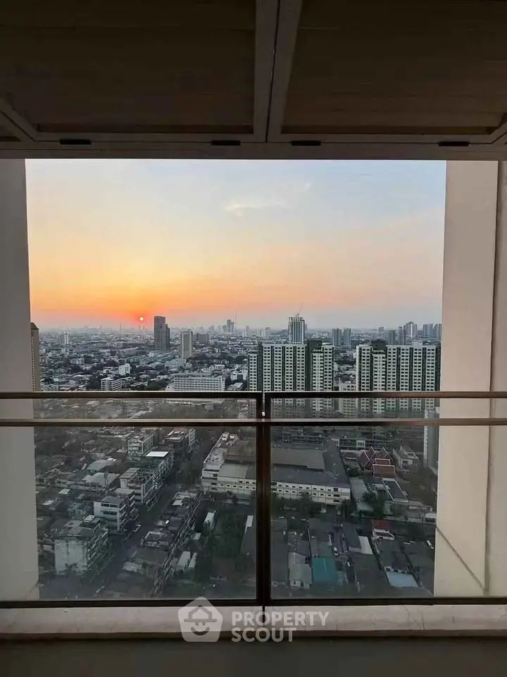 Stunning cityscape view from a high-rise balcony at sunset, showcasing urban skyline and vibrant horizon.