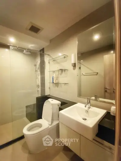 Modern bathroom with glass shower and sleek fixtures in contemporary apartment.