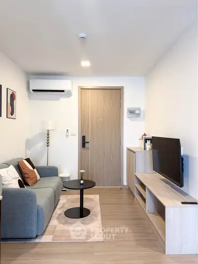 Modern living room with stylish decor and sleek furniture, featuring a cozy sofa and wall-mounted TV.
