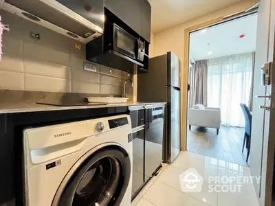 Modern kitchen with washing machine and stainless steel appliances in stylish apartment.