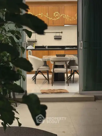 Elegant dining area with stylish chairs and wooden cabinetry, viewed from a cozy outdoor patio.