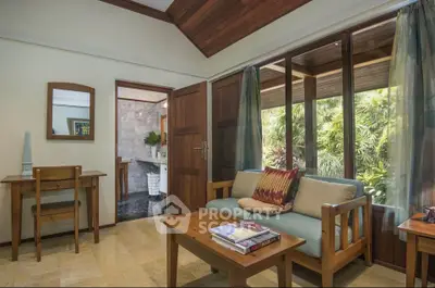 Charming living room with wooden ceiling and garden view, featuring cozy seating and natural light.