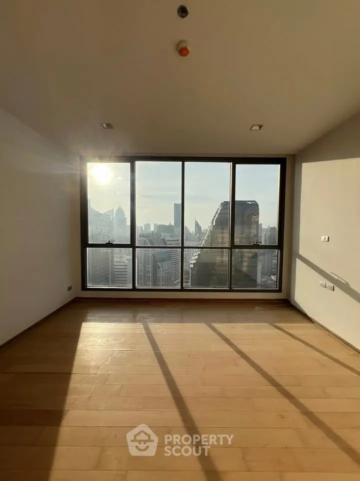 Spacious empty room with large windows offering stunning city skyline views and abundant natural light.
