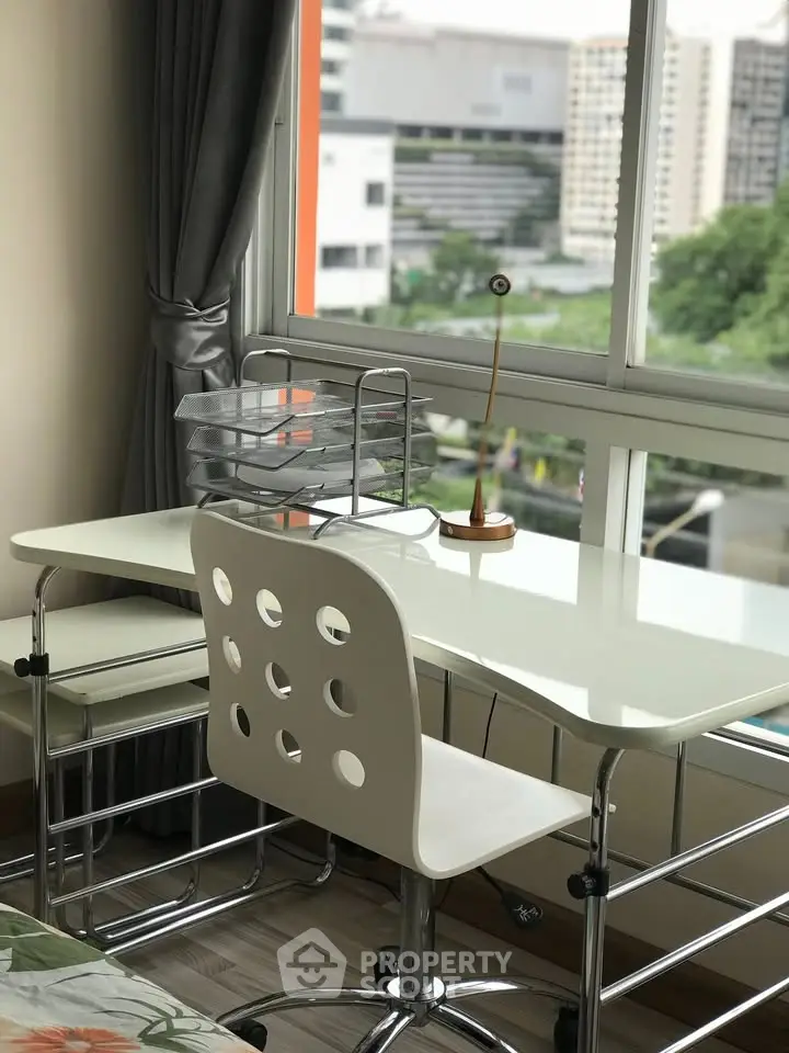 Modern study area with sleek desk and chair, large window offering city view, perfect for productivity.