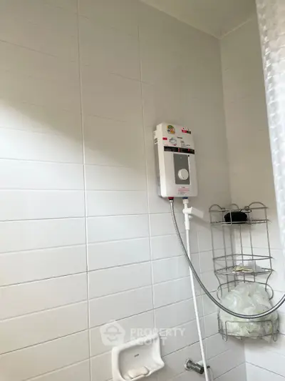 Modern bathroom with white tiled walls and electric shower unit.