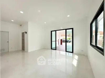 Spacious modern living room with large windows and sliding doors opening to a patio, perfect for natural light.