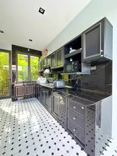 Luxurious kitchen with sleek black cabinetry and elegant marble countertops, featuring a bright and airy atmosphere.