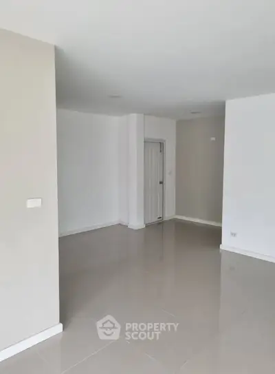 Spacious empty room with glossy tiled floors and neutral walls, ideal for customization.