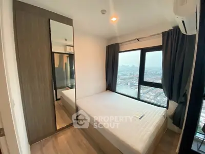 Modern bedroom with large window offering stunning city views and sleek wardrobe design.