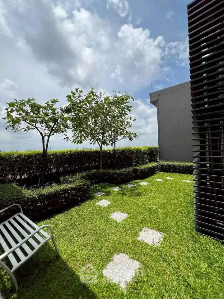 Lush green garden with stepping stones and modern outdoor seating, perfect for relaxation.