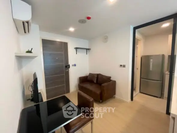 Modern compact living room with sleek furniture and open kitchen layout.