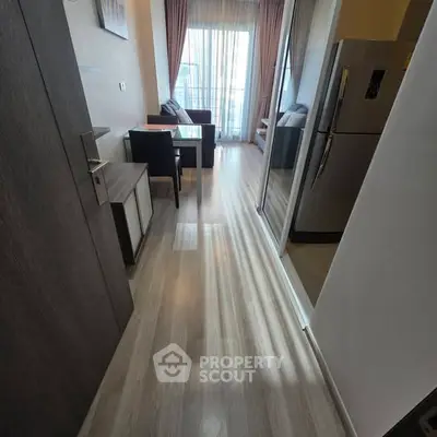 Modern apartment hallway leading to a cozy living area with natural light and sleek furnishings.