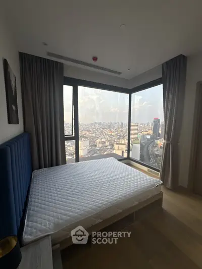 Luxurious bedroom with panoramic city view from floor-to-ceiling windows in modern high-rise apartment.