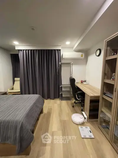 Modern bedroom with study area, featuring wooden flooring and sleek furniture design.