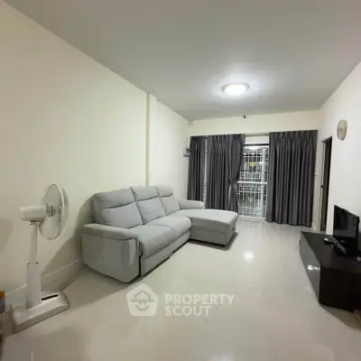 Spacious living room with modern gray sofa and sleek TV setup, perfect for relaxation and entertainment.