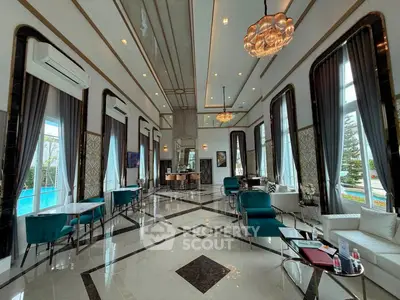 Luxurious living room with high ceilings, elegant decor, and pool view, perfect for sophisticated gatherings.