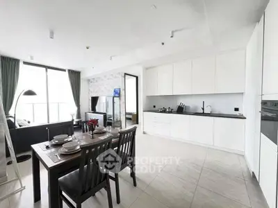 Spacious modern kitchen and dining area with sleek white cabinetry and elegant decor.