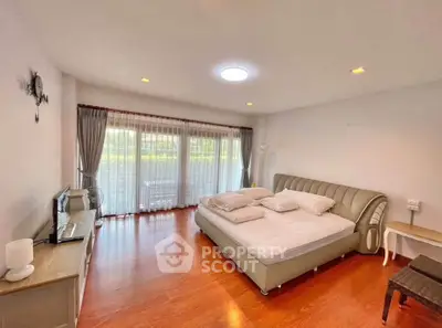 Spacious bedroom with elegant decor and large windows offering natural light.