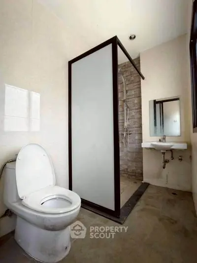 Modern bathroom with shower and toilet in minimalist design.