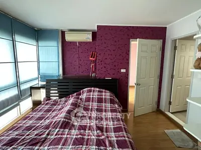 Spacious bedroom with a striking purple feature wall, large windows allowing ample natural light, and modern furnishings, perfect for relaxation and comfort.