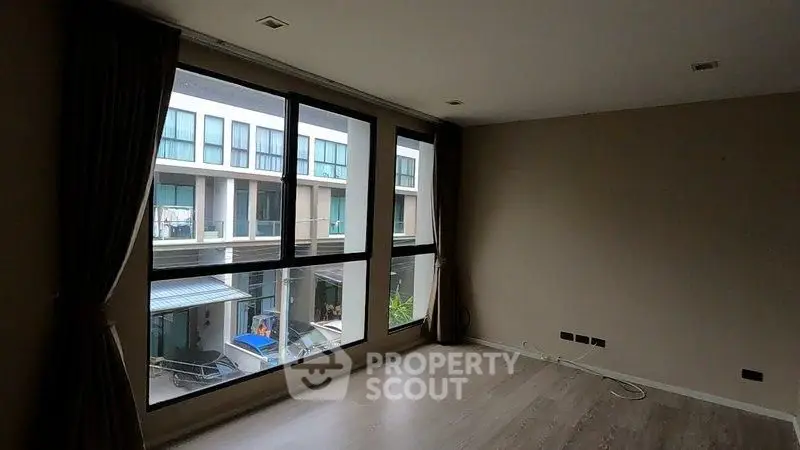 Spacious room with large windows offering a view of modern buildings, ideal for natural light.