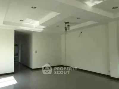 Spacious empty living room with modern ceiling lights and natural light.