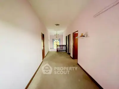 Spacious hallway with soft pink walls and elegant chandelier lighting.