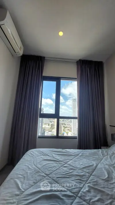 Cozy bedroom with city view through large window, featuring modern air conditioning and elegant curtains.