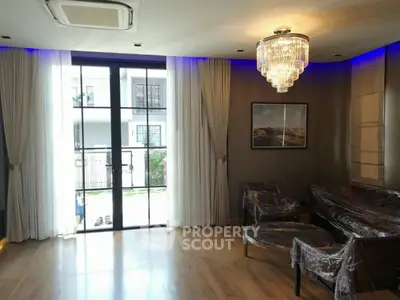 Luxurious living room with elegant chandelier and large windows opening to a balcony.