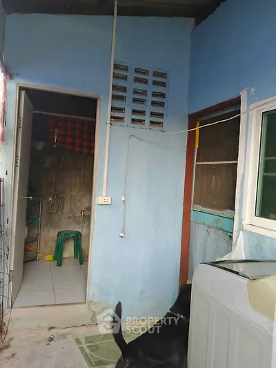 Simple laundry area with washing machine and bathroom access in a modest home.