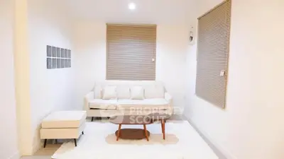 Modern living room with white sofa, cozy rug, and stylish coffee table in a bright, minimalist setting.