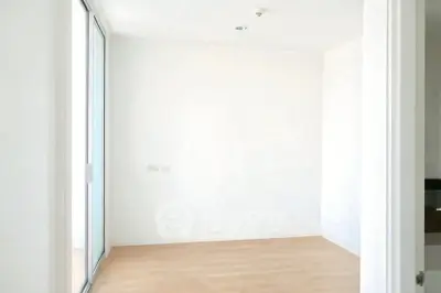 Spacious empty room with wooden flooring and large window for natural light