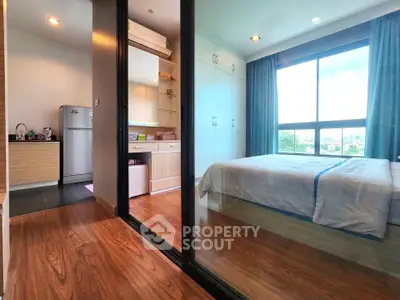 Modern apartment with glass partition, wooden flooring, and large window offering natural light.