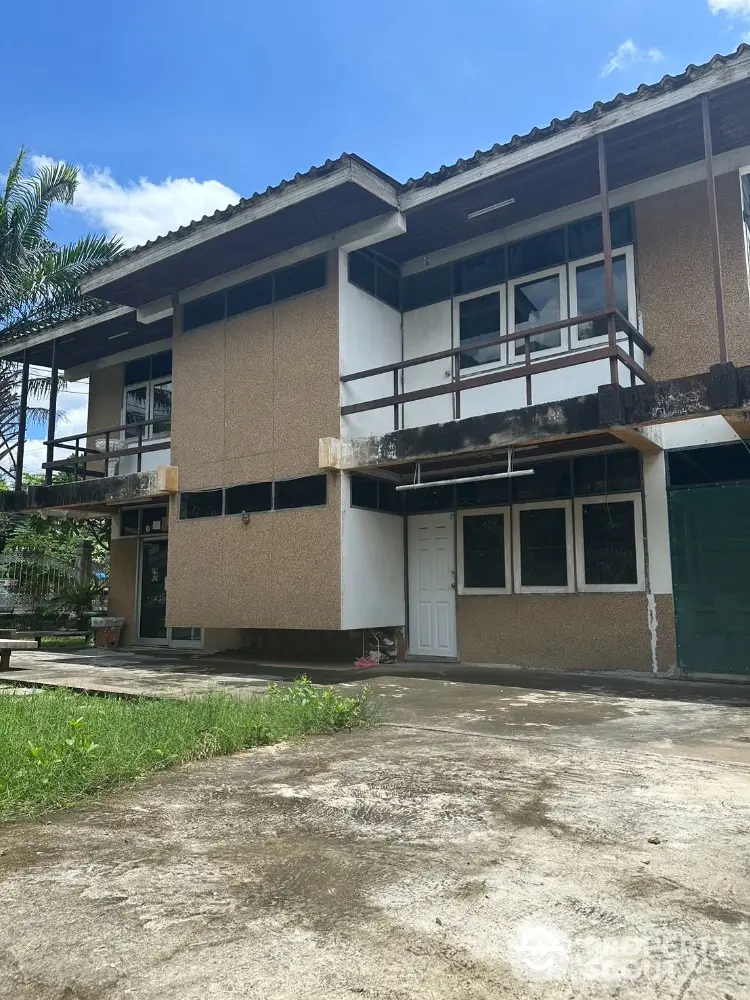 Charming two-story house with rustic design and spacious outdoor area under clear blue sky.