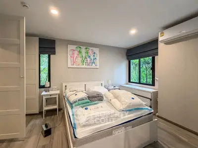 Modern bedroom with large windows and air conditioning, featuring stylish decor and ample natural light.