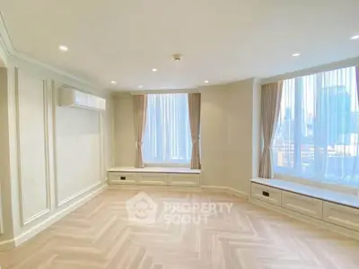 Spacious living room with large windows and elegant wood flooring in a modern apartment.