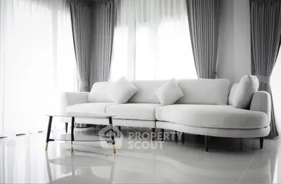 Modern living room with elegant white sofa and stylish coffee table, featuring floor-to-ceiling windows and chic curtains.