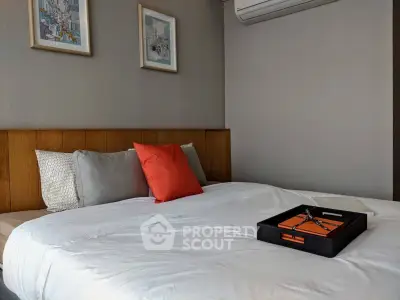 Modern bedroom with stylish decor and cozy bedding, featuring wall art and air conditioning for comfort.