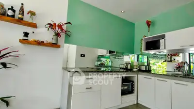 Modern kitchen with green accent wall, sleek white cabinets, and decorative plants.