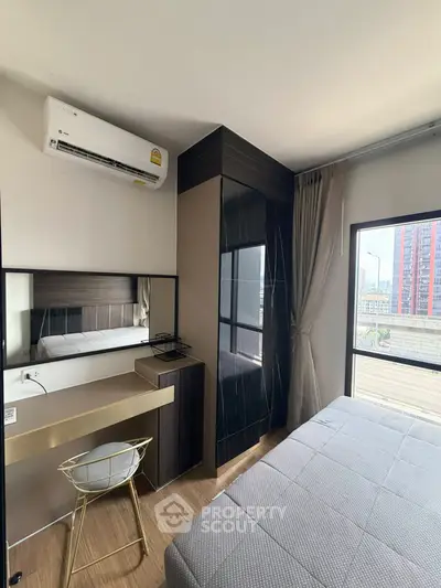 Modern bedroom with city view, featuring sleek furniture and large windows for natural light.